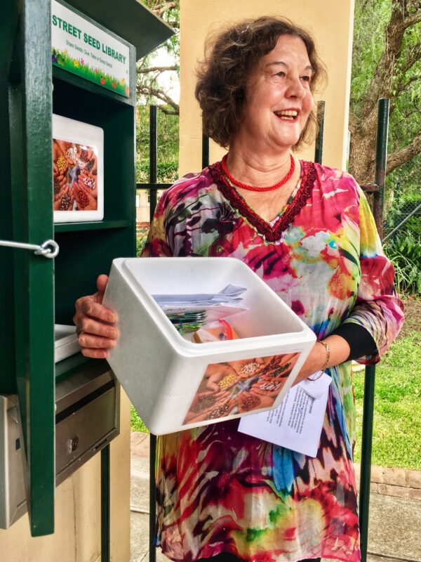 A woman stands holding a box of seeds